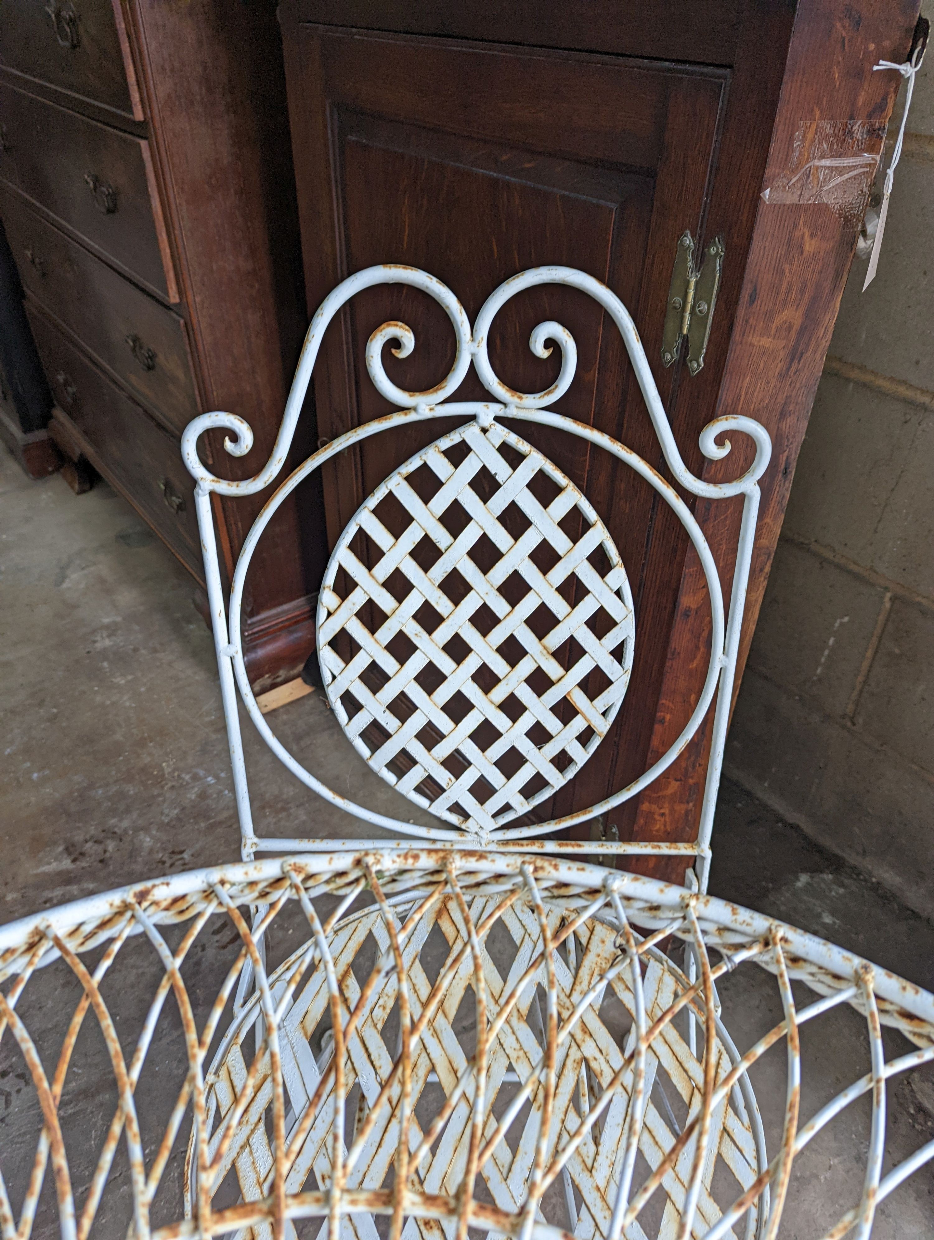 A circular painted wrought iron garden table, diameter 75cm, height 75cm together with four painted wrought iron folding garden chairs